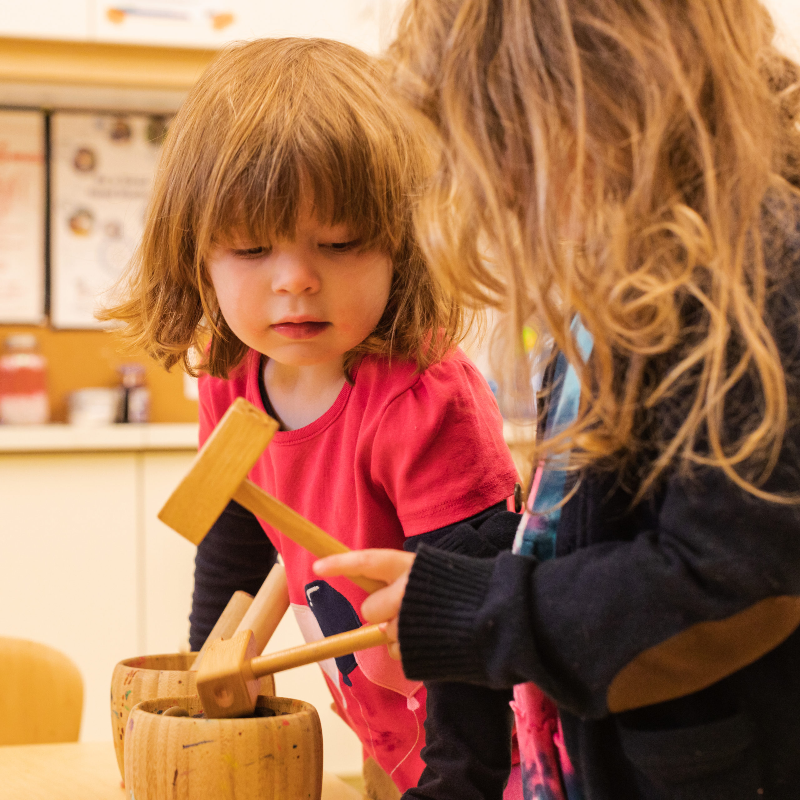 A little girl and her mom playing with wooden toys.