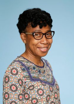 A woman with glasses and short hair wearing a dress.