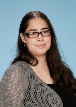 A woman with long hair wearing glasses and a black shirt.